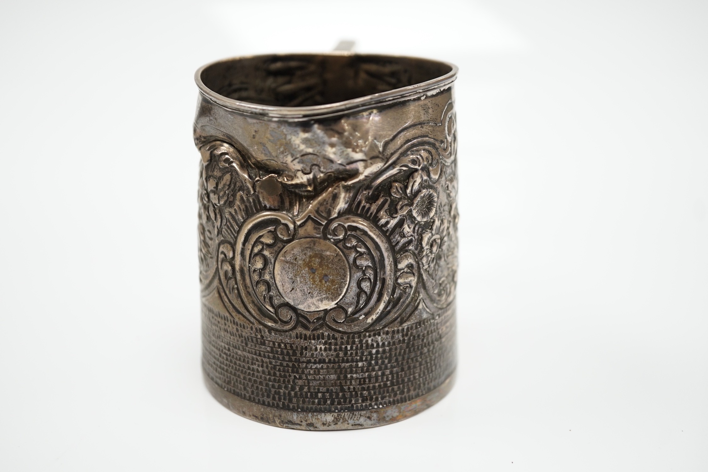 A George III silver mug, with later embossed decoration (af.), Charles Hougham?, London, 1812, height 81mm.